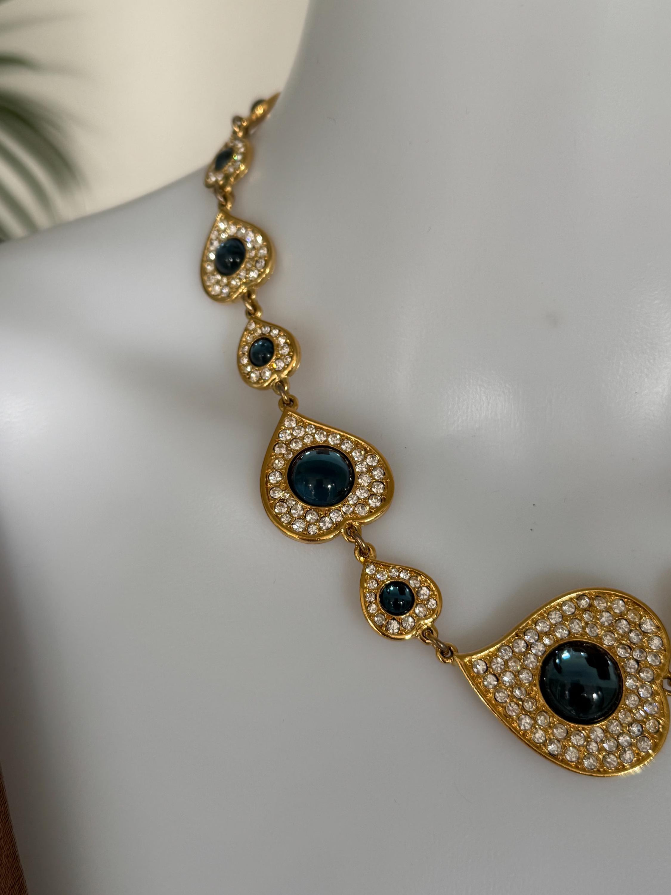 Close-up of Vintage YSL heart necklace featuring blue cabochon and crystal frame